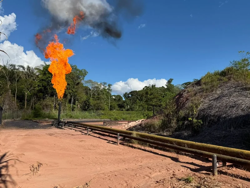 Tea de quema de gas residual encendida junto a la línea de conducción en una locación petrolera